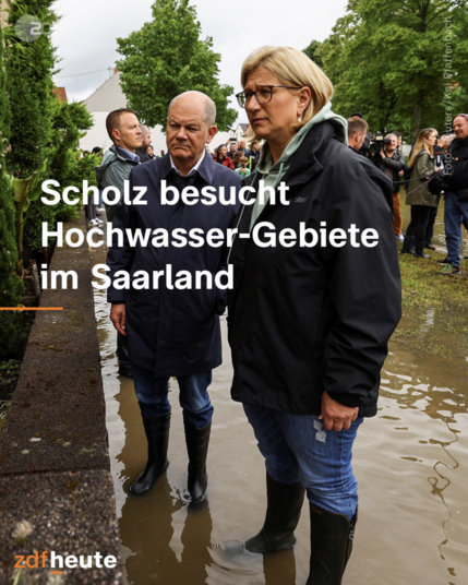 ZDF heute Bild zeigt Bundeskanzler Olaf Scholz und Saarländische Ministerpräsidentin Anke Rehlinger (beide SPD) in Gummistiefeln bei einem Besuch in der Gemeinde Kleinblittersdorf. Sie stehen am Rande des Hochwassers mit bestürztem Blick und betroffenen Gesichtern, auch die Körperhaltung drückt ihre Bestürzung aus. 