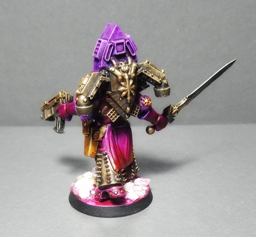 Assembled and painted miniature of a Warhammer 40k Noise Marine Miniature. He's wearing a Doom Siren and wielding a sword and a Bolter.
He's all kinds of purple and pink and his loincloth has a gradient from purple to orange.
Back View.