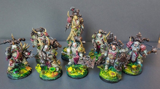 Photo of eight miniatures. All of them are Death Guard and their armour painting scheme is very oldschool with a lot of white and just a bit of green. All are mutated and sport mouths, teeth, maggots everywhere. One is a Apothecary on a slightly taller base.